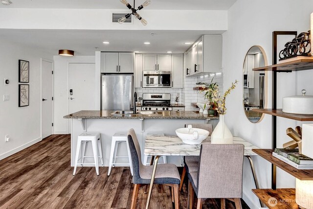 1420 Terry Ave Unit 603, Seattle, WA 98101 - kitchen with stainless steel appliances, a sink, stone countertops, a peninsula, and backsplash