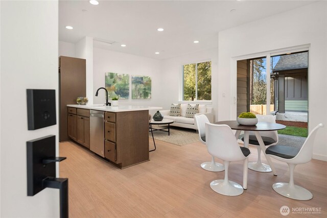kitchen with a sink, light wood finished floors, light countertops, recessed lighting, and stainless steel dishwasher