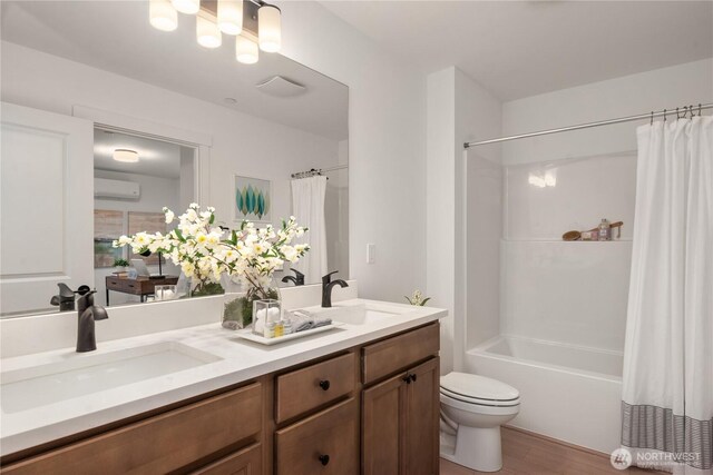 full bath featuring shower / bath combo, a sink, a wall mounted air conditioner, and toilet