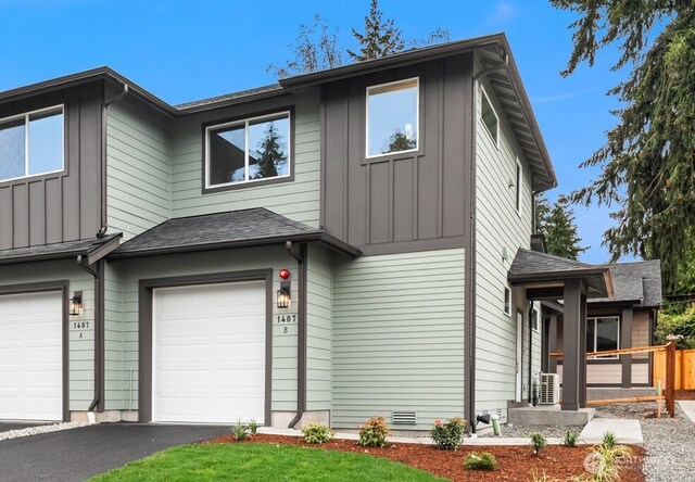 view of front facade featuring board and batten siding, an attached garage, fence, and aphalt driveway