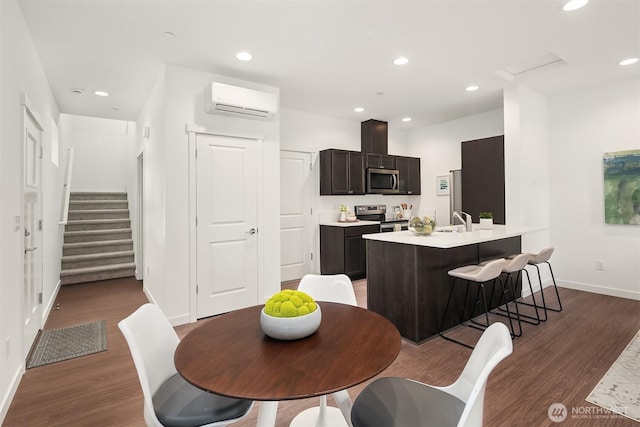 1240 SW 124th St Unit 10B, Burien, WA 98146 - kitchen featuring a wall mounted air conditioner, appliances with stainless steel finishes, wood finished floors, and light countertops