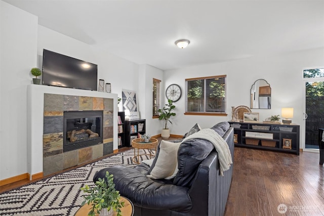 living room featuring baseboards, wood finished floors, and a tile fireplace