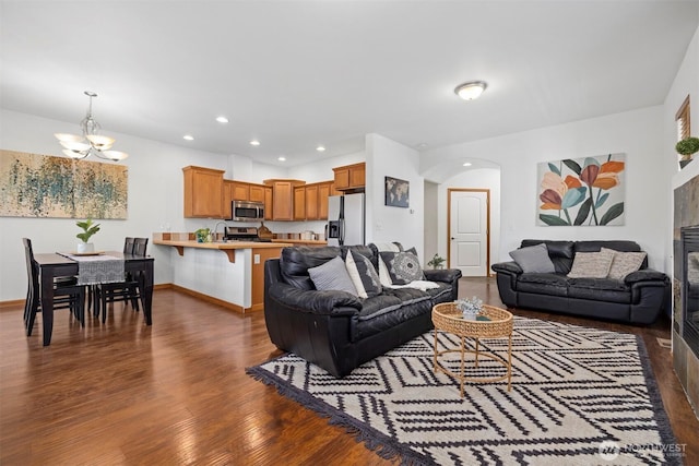 living area with wood finished floors, baseboards, recessed lighting, arched walkways, and a notable chandelier