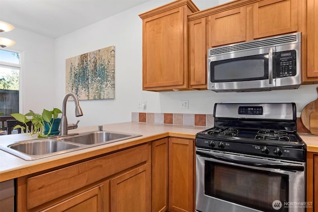 kitchen with light countertops, a sink, brown cabinetry, and stainless steel appliances