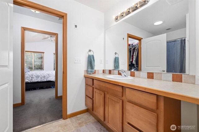 ensuite bathroom featuring vanity, baseboards, ensuite bathroom, and a spacious closet