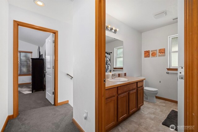 bathroom featuring visible vents, baseboards, a healthy amount of sunlight, and vanity