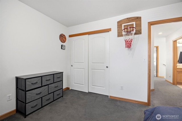 bedroom featuring dark colored carpet, baseboards, and a closet
