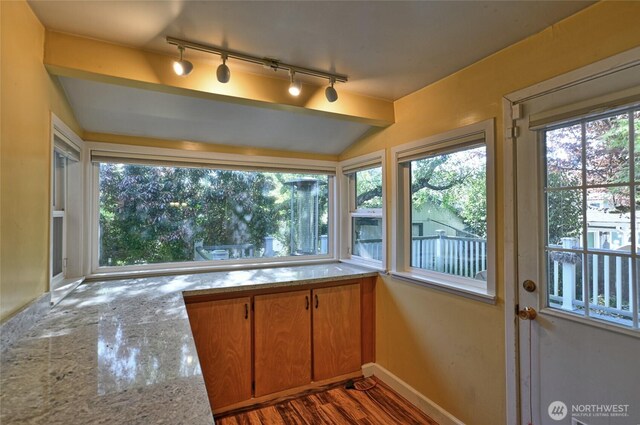 unfurnished sunroom with track lighting, plenty of natural light, and vaulted ceiling