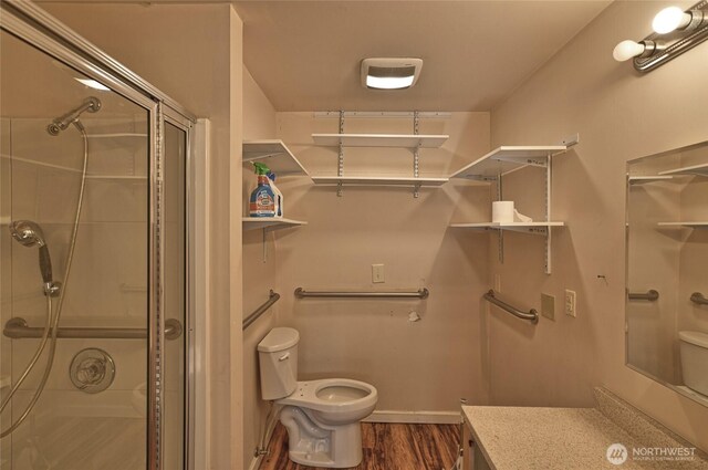 bathroom featuring toilet, a stall shower, wood finished floors, and vanity