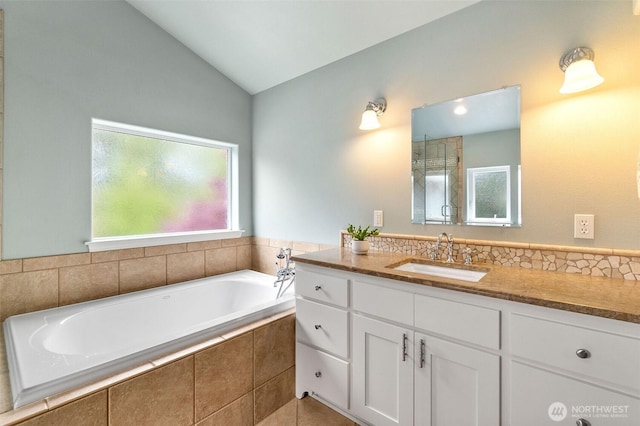 full bath with a garden tub, tile patterned flooring, vaulted ceiling, and vanity