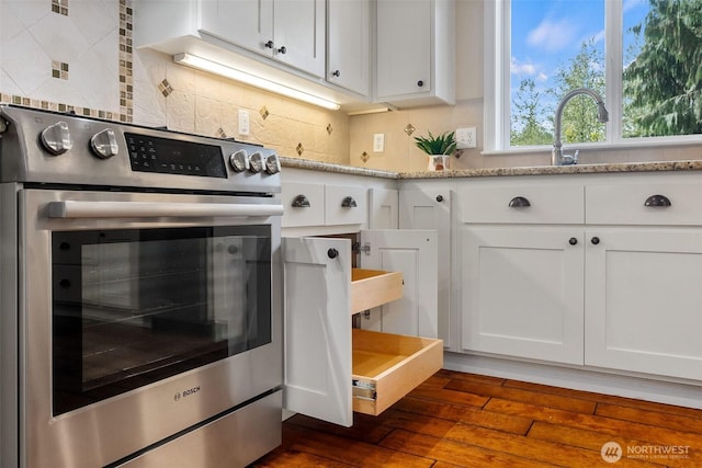 kitchen featuring oven, dark wood finished floors, white cabinets, and tasteful backsplash