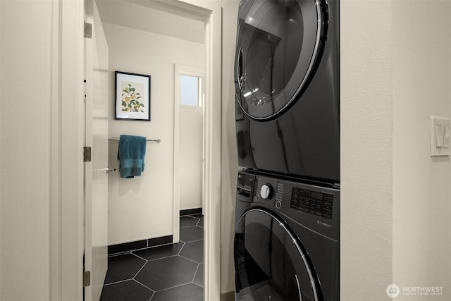 laundry area featuring laundry area, stacked washing maching and dryer, and dark tile patterned flooring