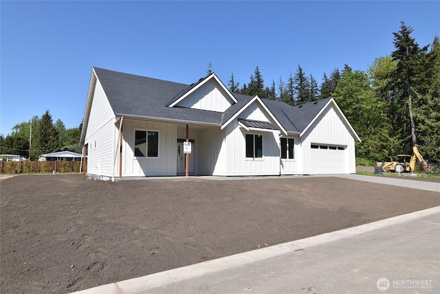 modern farmhouse style home featuring a garage, board and batten siding, driveway, and roof with shingles