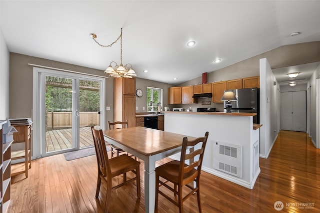 dining room featuring a notable chandelier, light wood-style flooring, and lofted ceiling