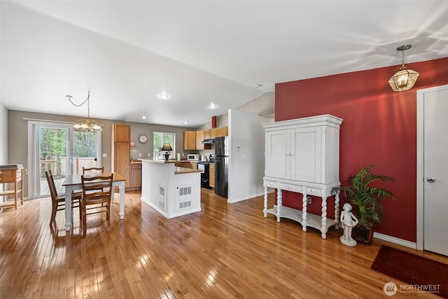 kitchen with decorative light fixtures, light wood-type flooring, freestanding refrigerator, a chandelier, and lofted ceiling