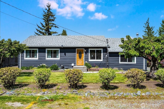 single story home featuring a shingled roof and a front yard