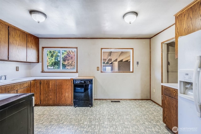 kitchen featuring light countertops, visible vents, brown cabinetry, and black appliances