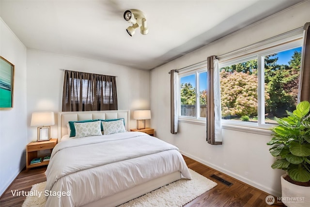 bedroom featuring baseboards, visible vents, and wood finished floors