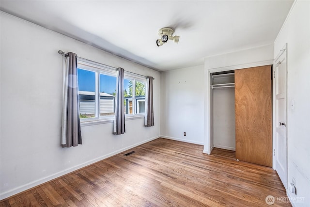unfurnished bedroom with baseboards, wood finished floors, and a closet