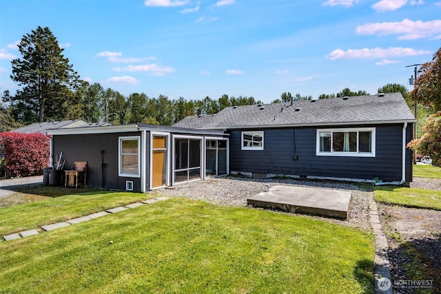 back of house featuring a sunroom, a lawn, and roof with shingles