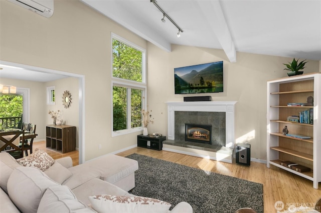 living room featuring wood finished floors, beamed ceiling, an AC wall unit, a tile fireplace, and rail lighting