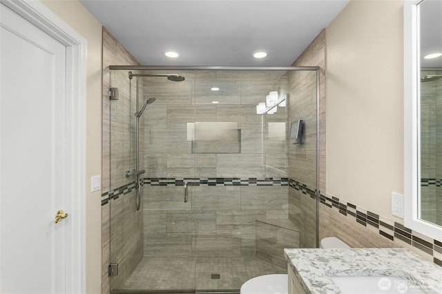 full bathroom featuring toilet, a stall shower, tile walls, and vanity