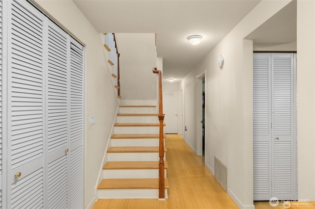 stairway featuring wood finished floors and visible vents