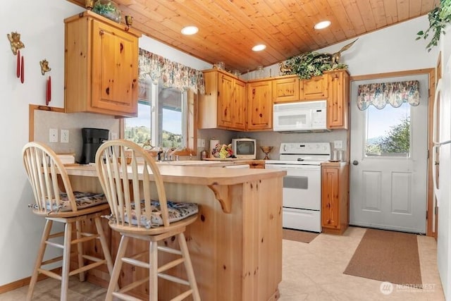 kitchen with a peninsula, white appliances, a kitchen breakfast bar, recessed lighting, and light countertops