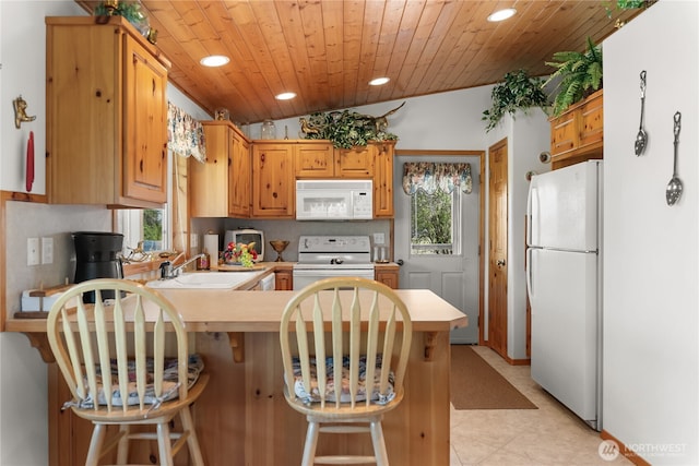 kitchen featuring white appliances, a peninsula, recessed lighting, and light countertops