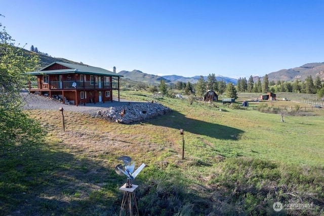 view of yard with a deck with mountain view and a rural view
