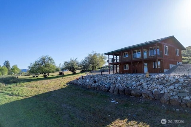 rear view of property featuring a yard and a balcony