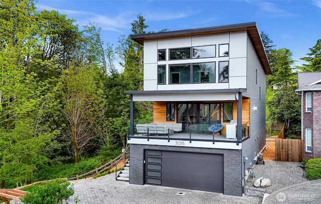 view of front of property with decorative driveway, an attached garage, fence, and outdoor lounge area