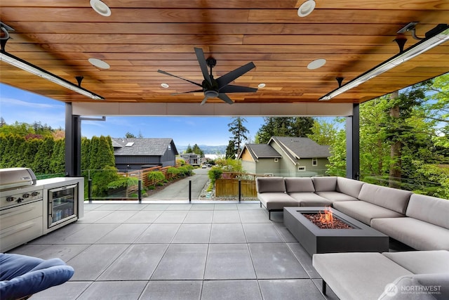 view of patio with a ceiling fan, an outdoor living space with a fire pit, wine cooler, and an outdoor kitchen