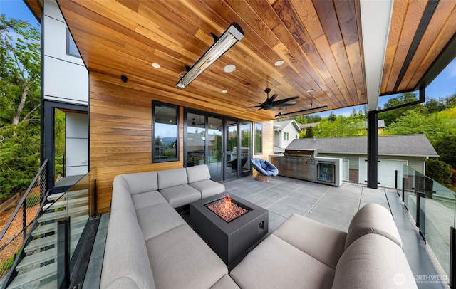view of patio / terrace featuring an outdoor kitchen, an outdoor living space with a fire pit, a ceiling fan, and beverage cooler