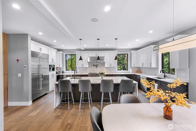 kitchen with appliances with stainless steel finishes, plenty of natural light, under cabinet range hood, and a kitchen bar