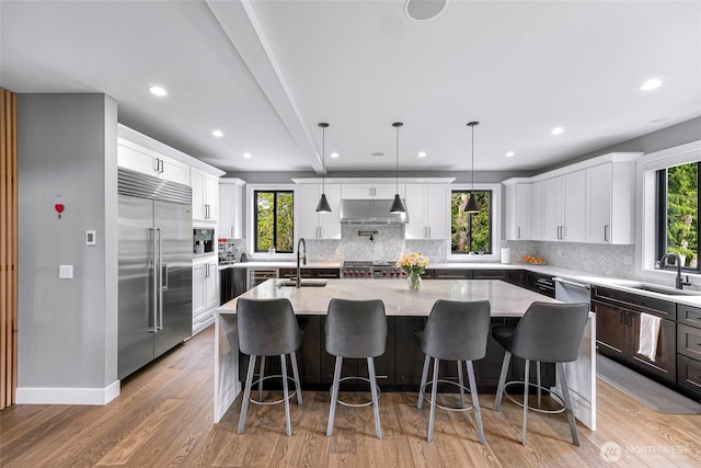 kitchen featuring under cabinet range hood, stainless steel appliances, a sink, and backsplash