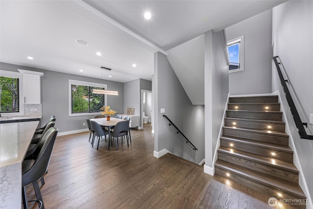 stairway with baseboards, recessed lighting, a healthy amount of sunlight, and hardwood / wood-style floors
