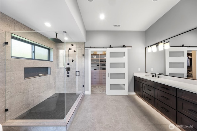 bathroom with a walk in closet, vanity, finished concrete flooring, visible vents, and a stall shower