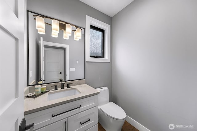 bathroom with toilet, wood finished floors, and vanity