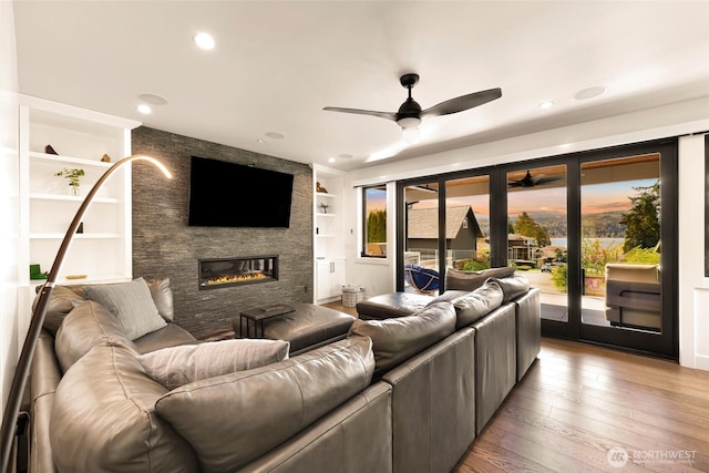 living area featuring plenty of natural light, ceiling fan, hardwood / wood-style floors, and a large fireplace