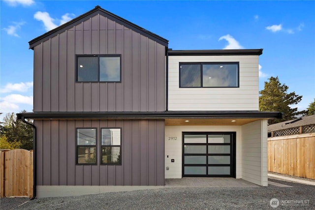 modern home with fence, board and batten siding, and an attached garage