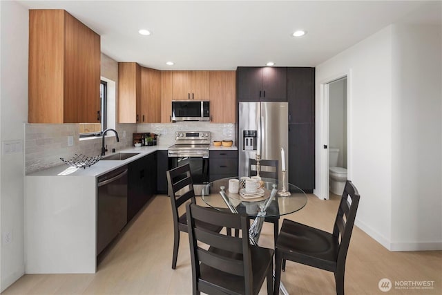 kitchen with appliances with stainless steel finishes, tasteful backsplash, a sink, light countertops, and recessed lighting