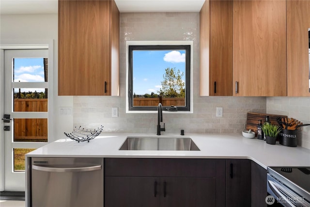 kitchen featuring a sink, light countertops, decorative backsplash, stainless steel dishwasher, and modern cabinets