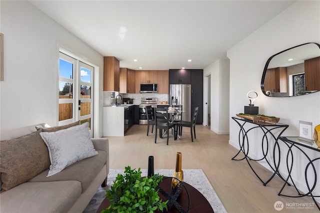 living room with recessed lighting, baseboards, and light wood-type flooring