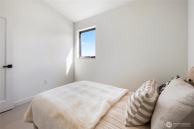 bedroom featuring baseboards, vaulted ceiling, and light wood finished floors