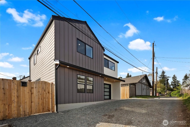 contemporary home featuring board and batten siding, fence, and driveway