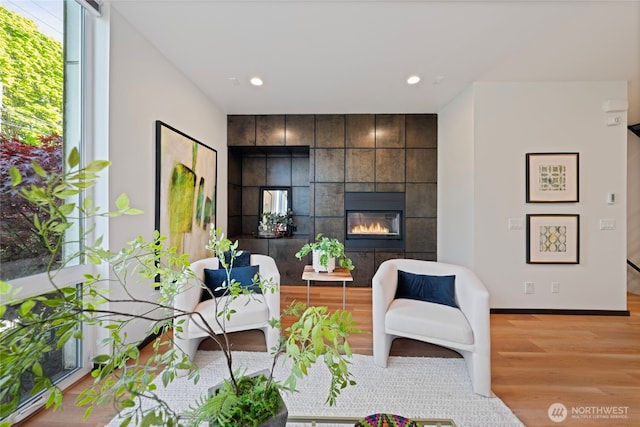 living area with baseboards, recessed lighting, wood finished floors, and a fireplace