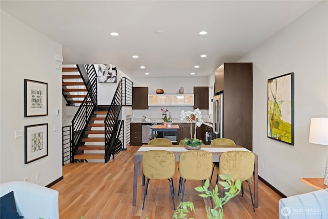 dining space with recessed lighting, baseboards, light wood-type flooring, and stairs