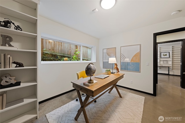 office space featuring baseboards and finished concrete floors