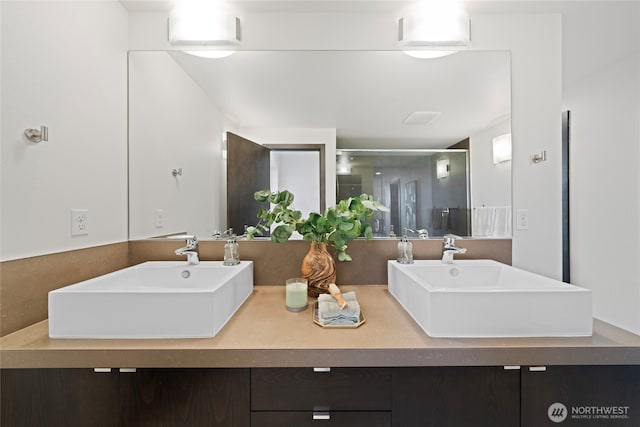 bathroom featuring double vanity, a sink, and a stall shower